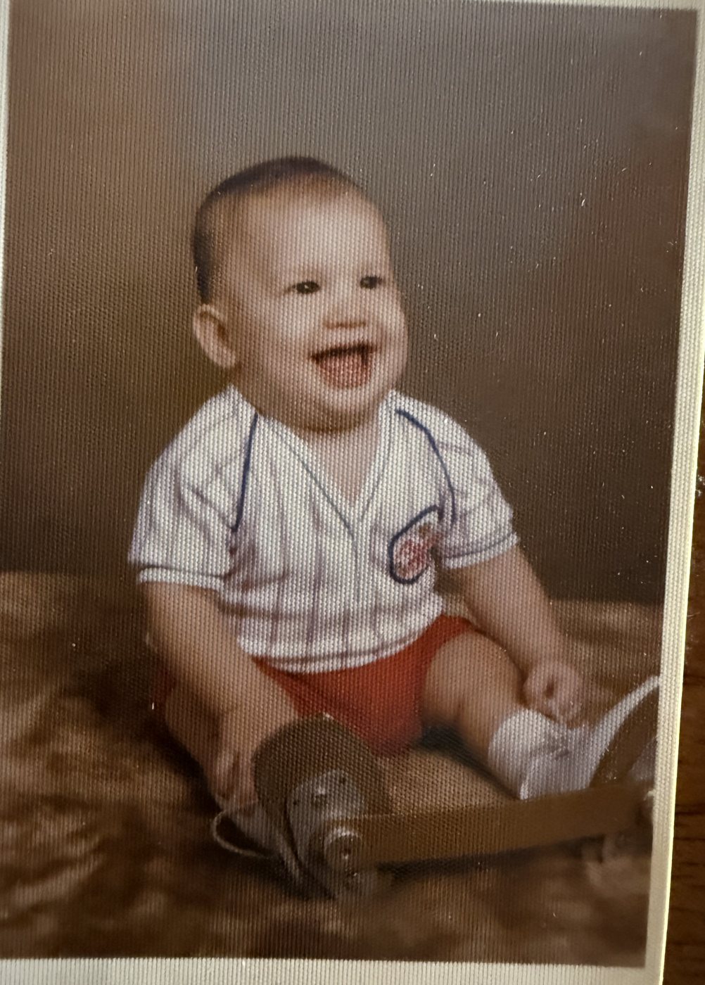 Baby Heath grinning in a studio portrait, both shoes fixed to a metal bar