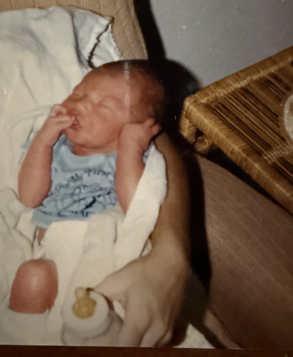 Newborn Heath held in a parent's arms, a cast visible on his leg