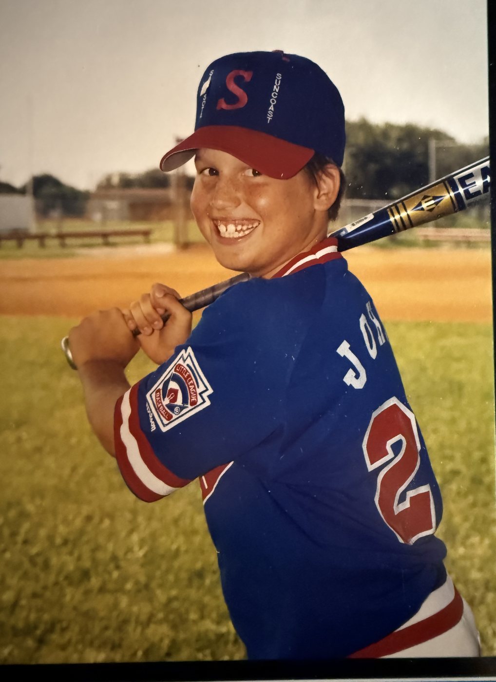 Heath as a boy in a Southeast All Stars uniform and cap, bat on his shoulder
